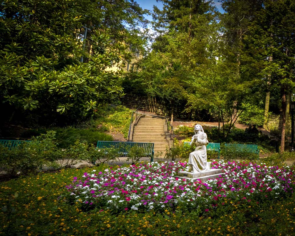 Saint Bernadette Soubirous kneeling in the garden before the Virgin Mary
