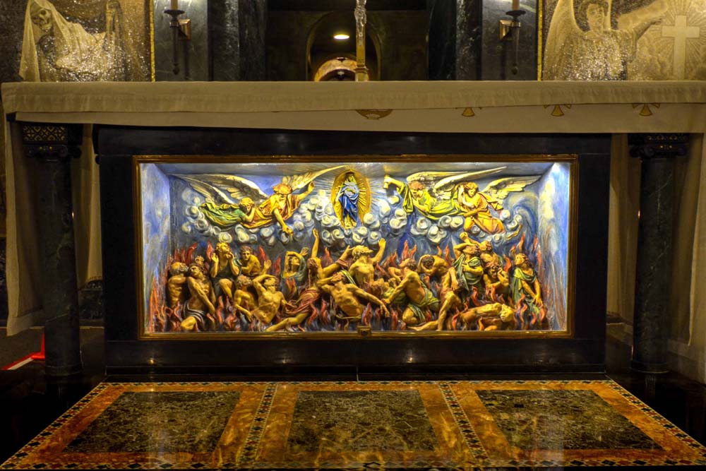Altar in the Purgatory Chapel with mosaics on the wall behind it and French deep-relief showing suffering souls in flames of purgatory